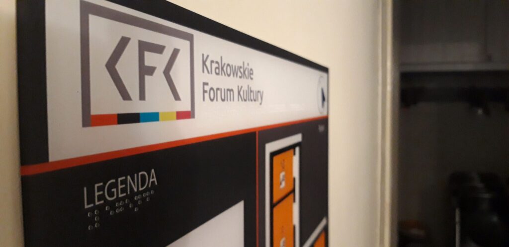 Tablica informacyjna Krakowskiego Forum Kultury z legendą przedstawioną również w alfabecie Braille’a oraz fragmentem planu budynku.