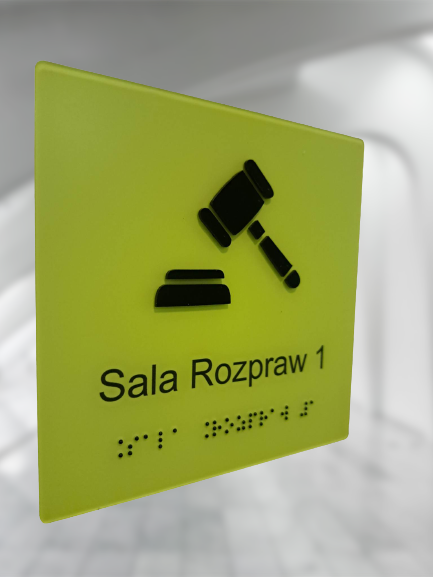 Tablica informacyjna „Sala Rozpraw 1” z piktogramem sali rozpraw oraz oznaczeniem w alfabecie Braille’a.