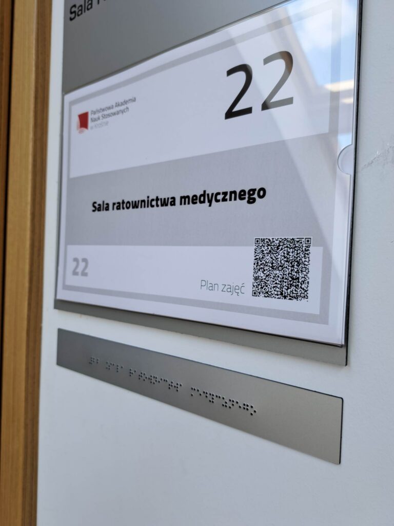 Tabliczka informacyjna sali ratownictwa medycznego z numerem 22 i oznaczeniem w alfabecie Braille’a.