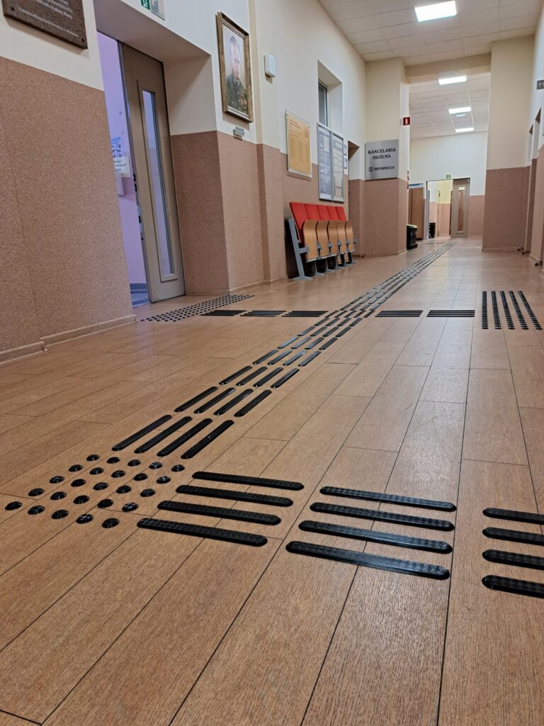 Korytarz z dotykową ścieżką prowadzącą dla osób niewidomych.