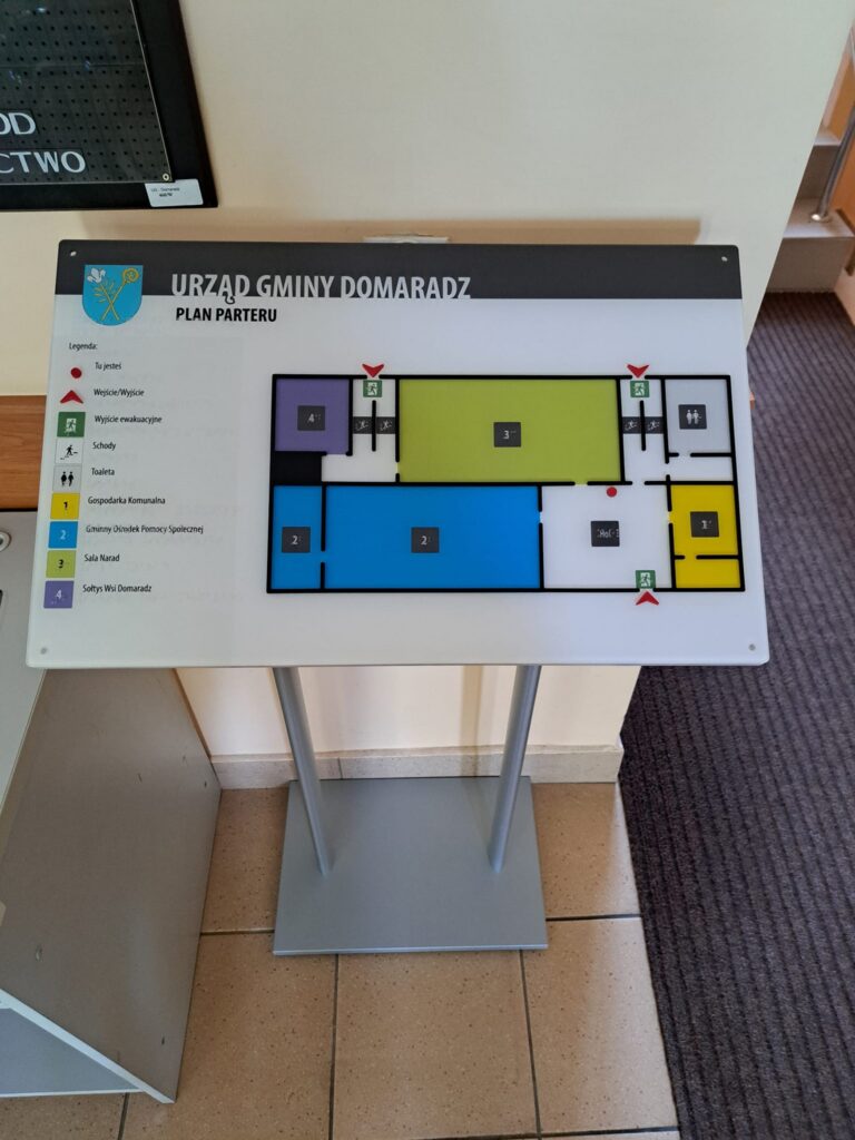 Plan parteru Urzędu Gminy Domaradz z legendą i oznaczeniami pomieszczeń, schodów, toalet oraz wyjść ewakuacyjnych.