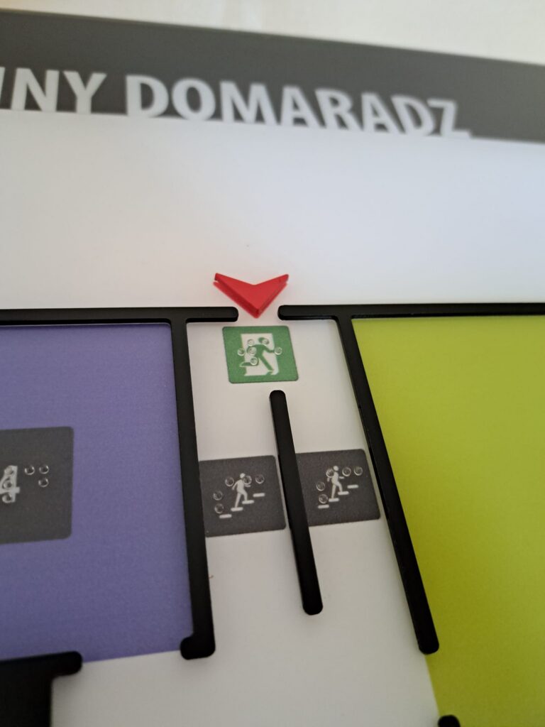 Zbliżenie planu tyflograficznego z oznaczeniem wyjścia ewakuacyjnego i schodów.