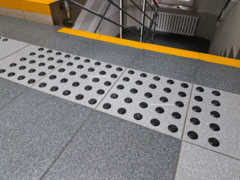 Pole uwagi przed schodami z żółtym oznaczeniem krawędzi.