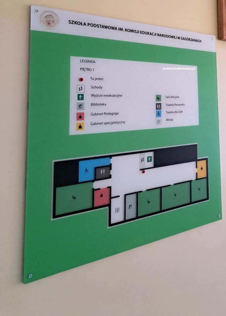 Tablica informacyjna z planem pierwszego piętra szkoły i legendą oznaczeń.