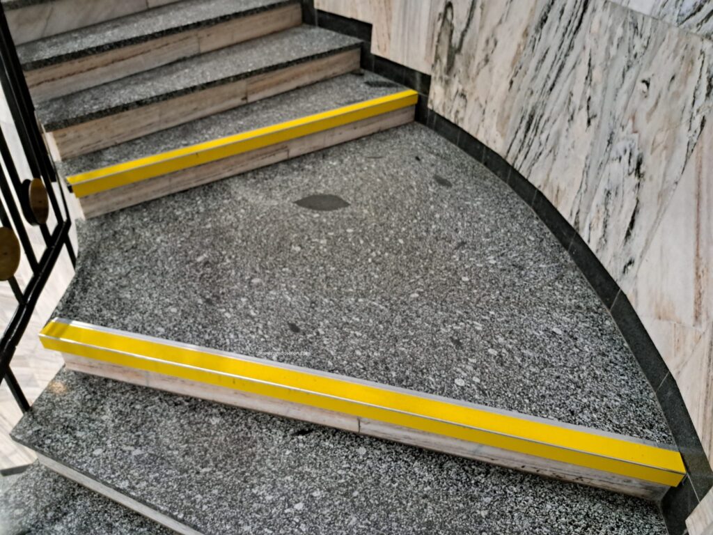 Schody z żółtymi oznaczeniami krawędzi stopni.
