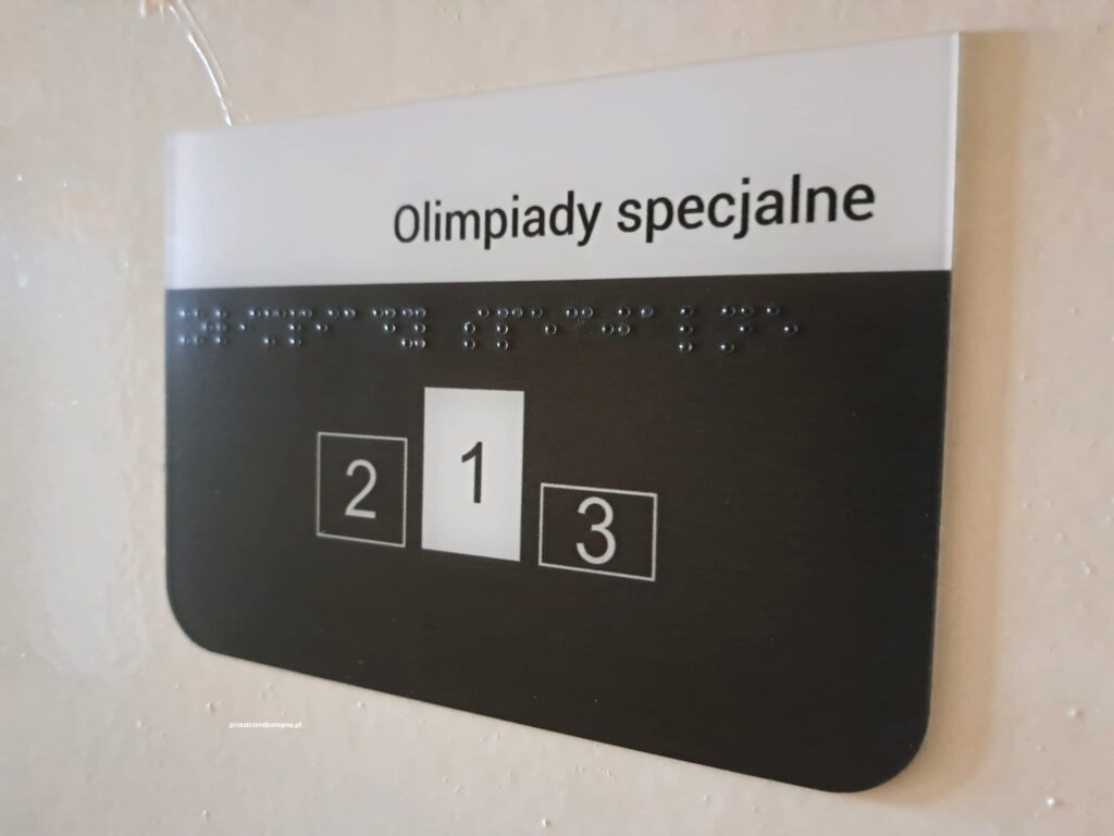 Tabliczka informacyjna „Muzykoterapia” z napisem w alfabecie Braille’a.