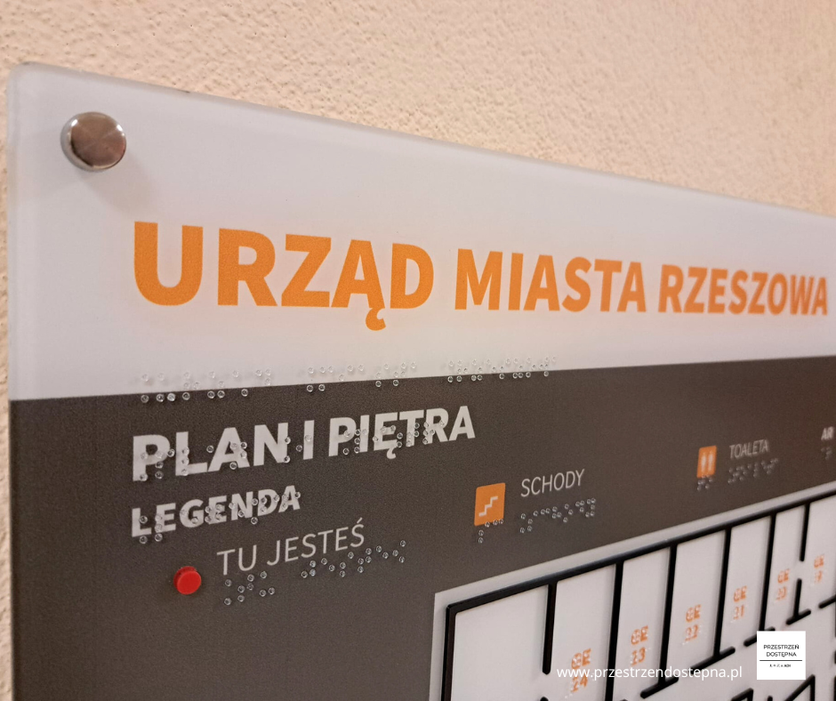 Dotykowy plan piętra z oznaczeniami pomieszczeń, schodów i punktu orientacyjnego.