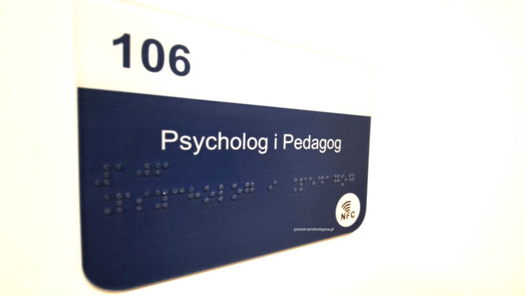 Tabliczka drzwiowa sali 106 z napisem „Psycholog i Pedagog”, numerem sali, oznaczeniem w alfabecie Braille’a i symbolem NFC.